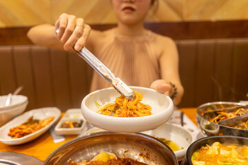 Lady tonging Korean noodle in Korea restaurant, enjoying traditional asian food. Food and travel concept