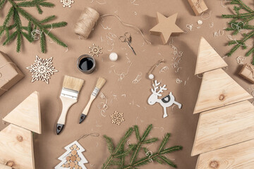 XMAS or New Year composition. Wooden Christmas trees, paint, brushes and fir branches on craft beige background. Concept Zero waste, eco - friendly Merry Christmas. Top view Flat lay