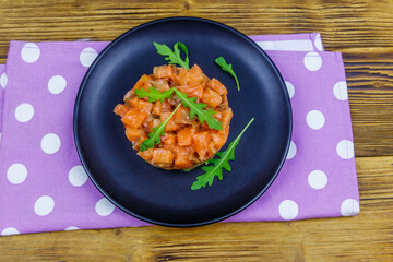 Salmon tartare with avocado and arugula on wooden table. Top view
