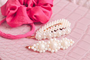 Set of pearl hairpins and elastic bands on pink background