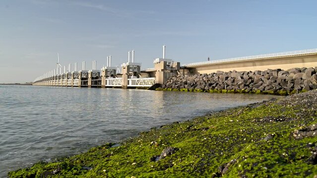 Static wide angle shot of a storm surge barrier in the Netherlands during a warm sunset