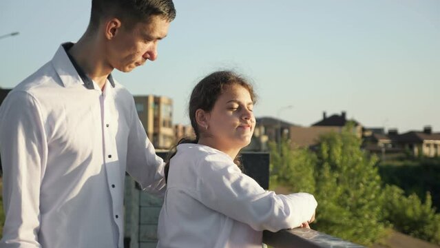 Young man with cerebral palsy comes to stylish disabled woman on bridge. Couple stands on bridge smiling to each other. Sun lights faces of lovers on sunny day