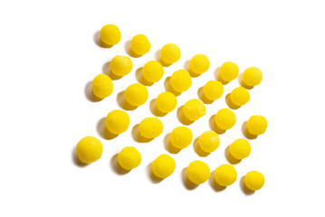 a lot of yellow round candies are laid out in a row on a white background on top of the frame, in perspective