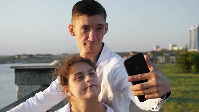 Young couple with cerebral palsy makes selfies on smartphone. Man and woman enjoy spending time together. Couple records bright moments on phone closeup
