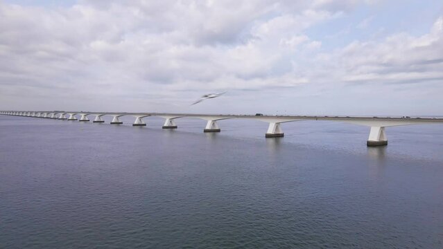 beautiful drone flight over the water from the eastern schelde to the Zeeland bridge under a cloudy sky