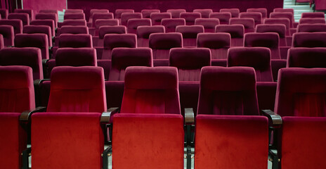 Empty red chairs for audience in the theater