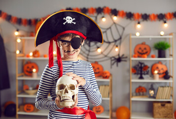 Portrait of smiling small boy kid child in costume hold skull celebrate school Halloween carnival....