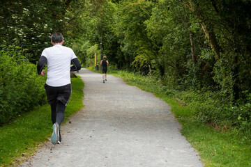 People running on a small foot path in a park. Jogging on fresh air. Sport and fitness concept.