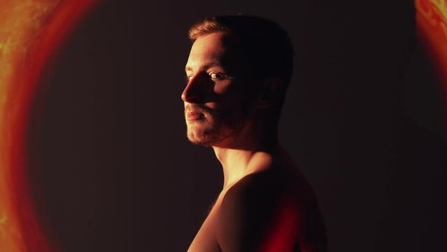 Spiritual energy. Esoteric healing. Freedom vitality. Tranquil calm shirtless man in red orange color fire flame smoke cloud swirl projector light.