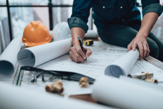 Engineering working with drawings inspection on the office desk and Calculator, triangle ruler, safety glasses, compass on Blueprint. Engineer, Architect, Industry and factory concept.