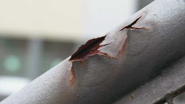 Peeled rust of corroded iron staircase handrail with cracked metal surface close up