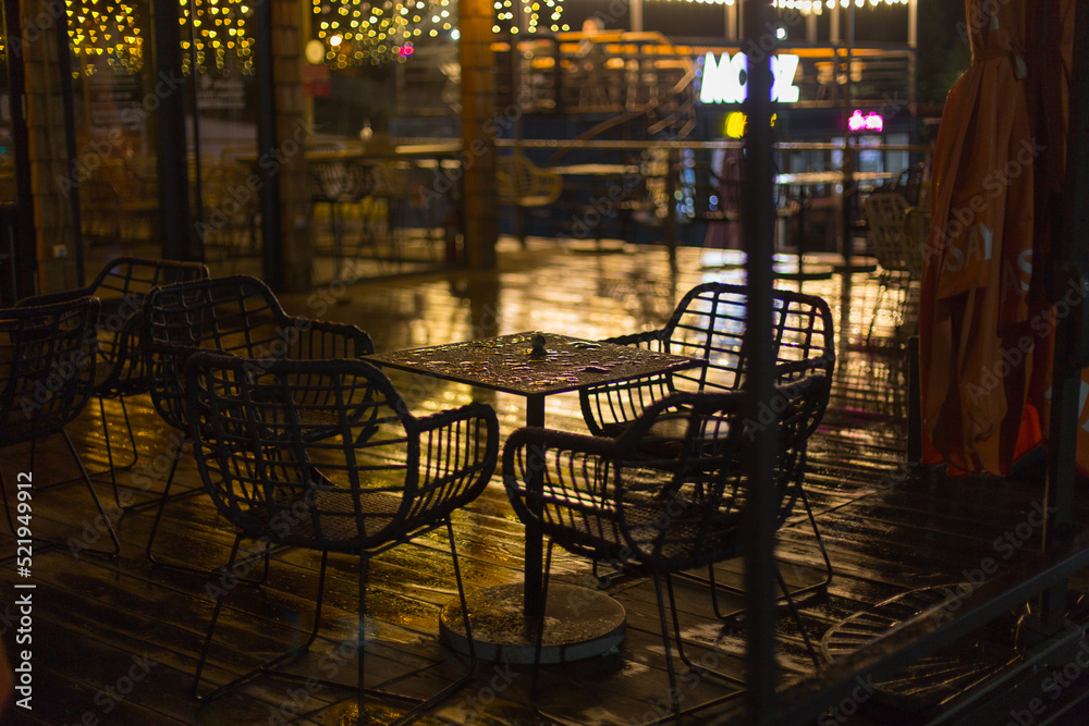 Wall mural chairs in a street cafe in the light of lanterns after the rain in the evening - Wall murals