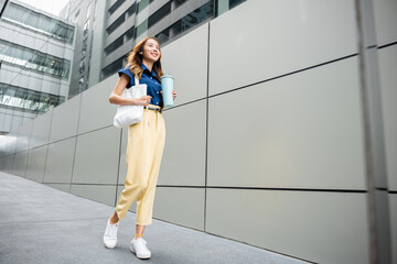 Asian beautiful business woman confident smiling with cloth bag holding steel thermos tumbler mug water glass she walking outdoors on street near modern building office, Happy female look forward - Powered by Adobe