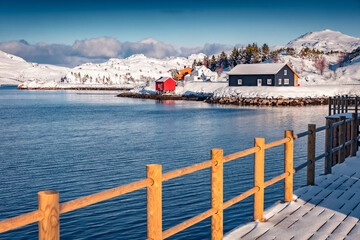 Wooden houses and empty pier on small fishing port - Ramberg, Norway, Europe. Frosty morning seascape of Norwegian sea. Bright winter scene of Lofoten Islands, Rambergsvika fjord.