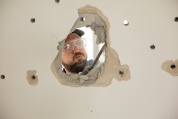 A man forges a hole in the wall with a hammer impact drill hollow space drilled out. A focused...