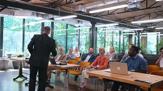 Video of a business conference meeting with an educator speaking to the people in the room. Cinematic footage representation of public speaking concepts and self improvement motivational summits