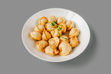 Fried dumplings on white plate on gray.