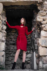 Young girl in the red dress walks on the ancient ruins.