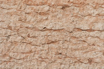 Texture of cracked beige stone rock wall. Old building. Neutral pastel colour background