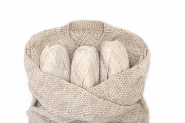 Knitted sweater hugs skeins of yarn on white isolated background. Concept of knitting, sewing. Copy space