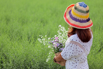 A woman in a vintage dress holds a bouquet of flowers alone in the morning in the green grass...