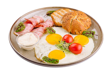 Plate of breakfast with fried eggs, bacon and toasts isolated on white