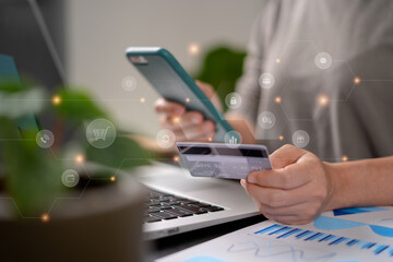 Close up shot of females hands holding credit card typing message on smart phone with technology icons for shopping online.