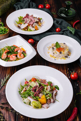 different salads in white plates on a wooden table