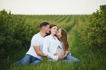 Naklejka na ściany i meble Pregnant woman with her family looking happy