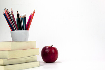 Education materials in the box, red apple and books isolated on white background. Back to school poaster concept templates