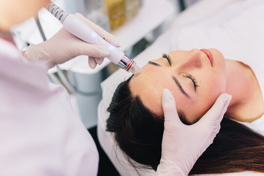 Cosmetologist doing hydrafacial treatment on woman face