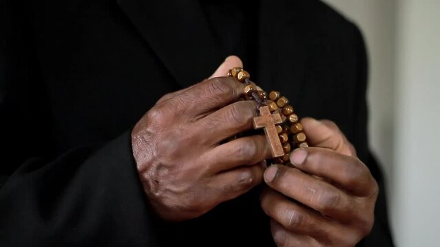 man praying to god with hands holding cross on black background stock footage