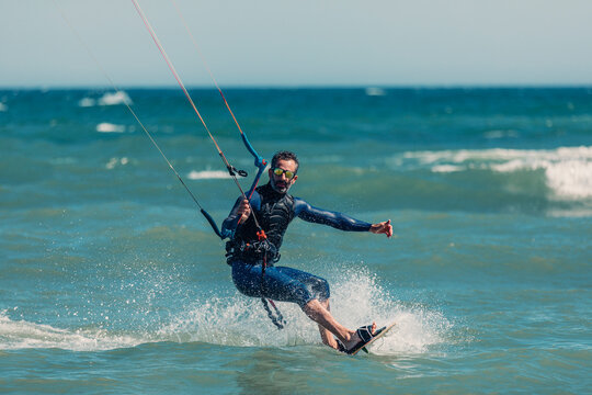 Man wearing wetsuit kiteboarding in sea on sunny day