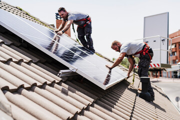 Technicians installing solar panels on rooftop