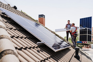 Electricians installing solar panels on rooftop
