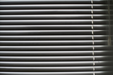 Obraz premium Part of the blinds with the adjustment handle is illuminated by daylight