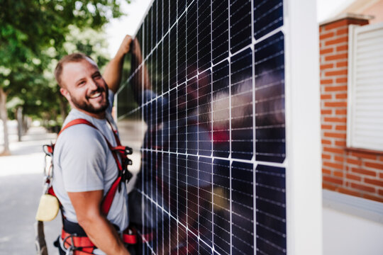 Smiling technician carrying heavy solar panel