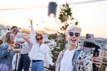 Caucasian young man make a video from rooftop party with friends in summer day
