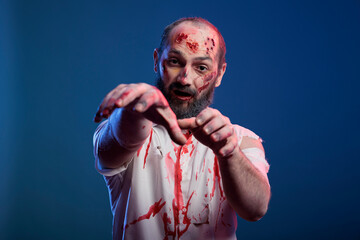 Creepy zombie growling at studio camera, having ugly bloody scars and wounds with undead creepy...
