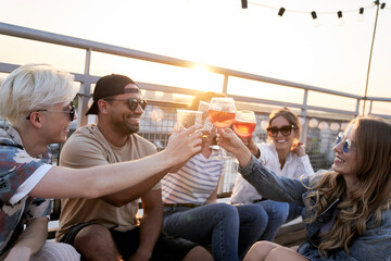 Group of friends make a toast during the sunset at the top of the roof