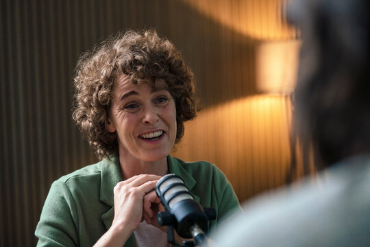 Happy presenter discussing with guest at radio station