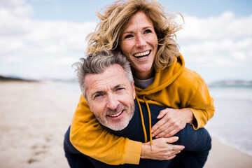 Happy man giving piggyback ride to woman at beach