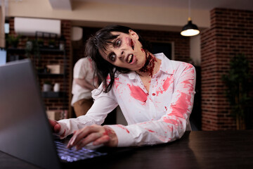 Aggressive devil corpse looking at laptop, sitting at office desk and being dangerous. Brain eating...