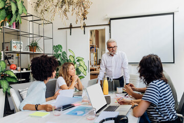 Senior manager conducting meeting with colleagues at work place