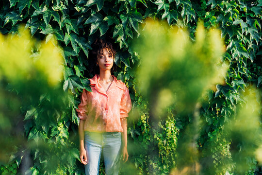 Young woman standing amidst green plants - Powered by Adobe