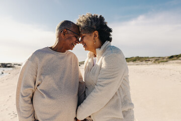 Elderly couple touching their heads together at the beach