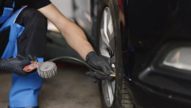 Mechanic inflating a car tire. Gas pumping of a car wheel. Car tire inflation. Car tire pressure check using air pressure guage