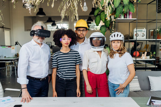 Multiracial business colleagues wearing different glasses and helmets in office
