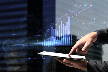 Close up of businessman hand pointing at pad with abstract glowing polygonal business graph...