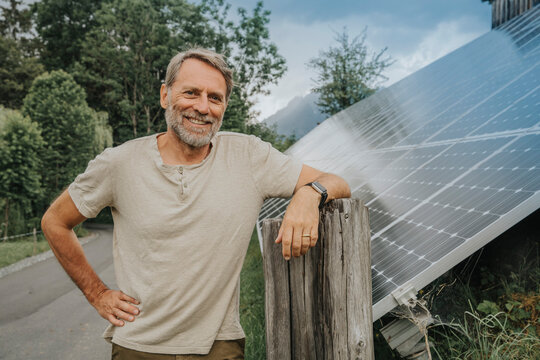Smiling mature man standing on road by solar panel